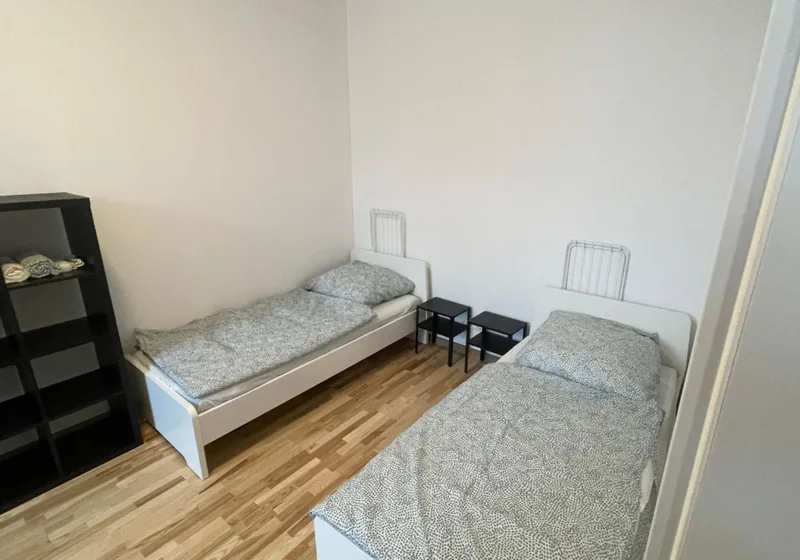 Helles Zweibettzimmer mit weißen Einzelbetten und Nachttischen